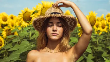 Woman with hat in front of sunflowers